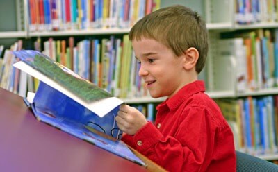 Photo of young boy reading in library