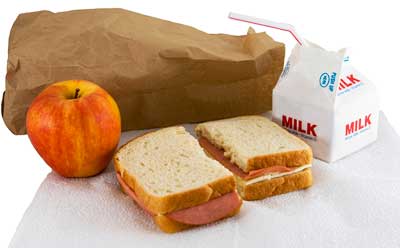 Photo of a brown bag lunch: sandwich, apple and milk