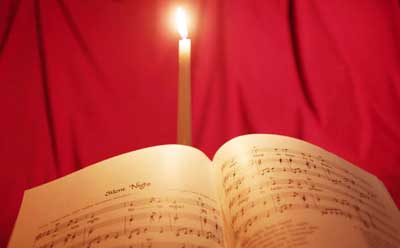 Photo of "Silent Night" sheet music illuminated by candlelight