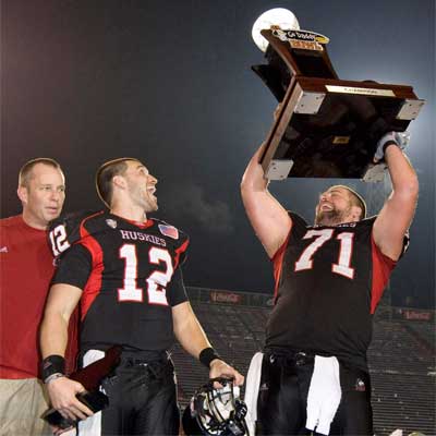 Scott Wedige hoists the trophy while Dave Doeren and Chandler Harnish look on.