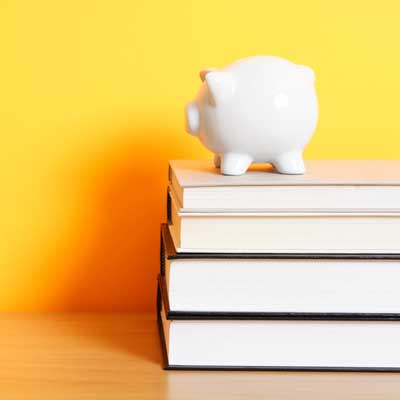Photo of a piggy bank on a stack of textbooks