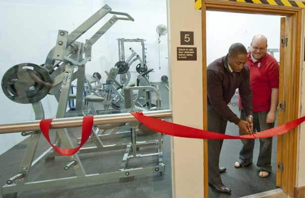 Student Association President Elliot Echols cuts the ribbon to the Rec Center Fitness Room as SA Speaker Austin Quick watches.