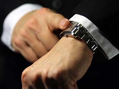 Photo of an man’s index finger tapping his wristwatch