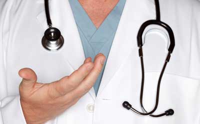 Image of a health care professional with white lab coat, blue scrubs and stethoscope