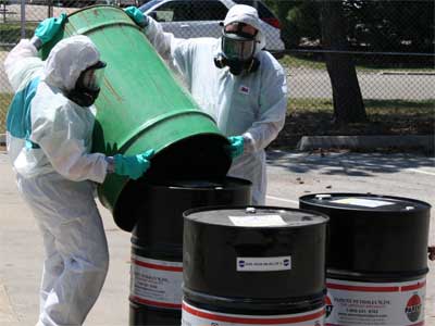 Elicia Bailey and Ryan Sego prepare oil drums for transport