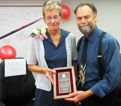 Steve Cunningham, vice president for Administration and Human Resources, presents Pat Siebrasse with the first “Patricia S. Siebrasse Administrative Professionals Award for Excellence.” Her beloved chair is on the left.