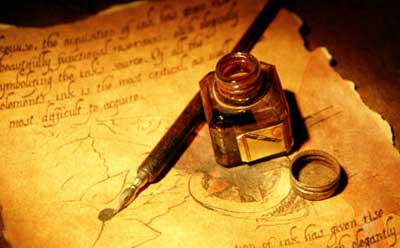 Photo of a bottle of ink and brush on parchment with writing