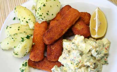 Photo of a dinner plate of fish sticks, potatoes, creamy seafood salad and a lemon wedge