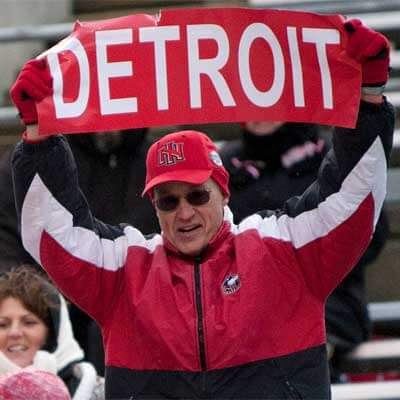 Photo of an NIU football fan with a "DETROIT" sign