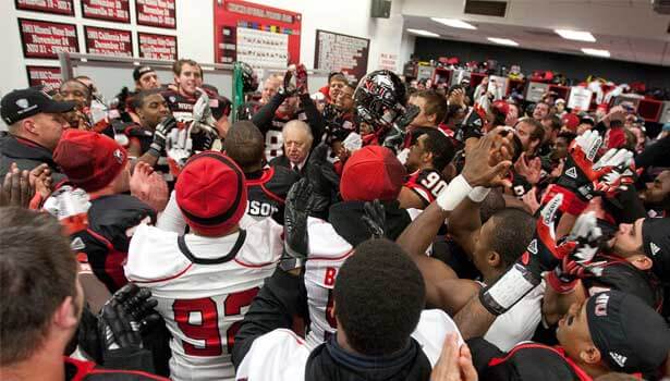 NIU President John Peters celebrates with the football team in the locker room after Wednesday night's 31-24 victory over Toeldo.