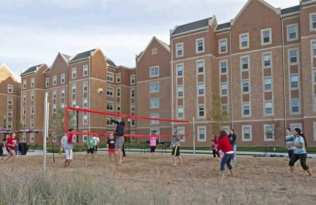 Students play volleyball on the sand court outside the New Residence Hall.
