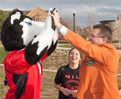 Victor E. Huskie high-fives Larry Gautier, a member of the football committee for the Discover Orange Bowl.