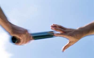 Photo of one hand passing the baton to the next