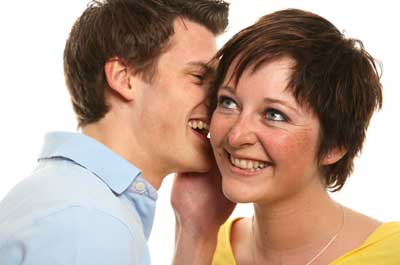 Photo of a man whispering into a woman's ear