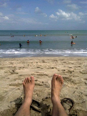 A photo of bare feet on a sandy beach on the ocean