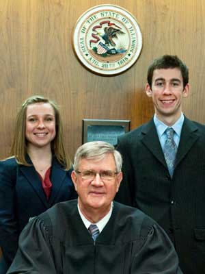 Second-year NIU Law students Amanda Wielgus and Anthony Gough stand with Chief Judge Michael P. McCuskey of the United States District Court for the Central District of Illinois.
