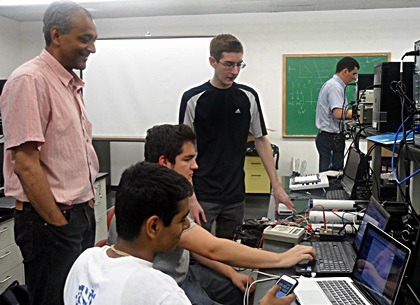 NIU physicist Dhiman Chakraborty observes the students' progress in setting up their cosmic ray detector.