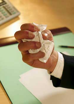 Photo of an office worker’s hand crumpling a piece of paper