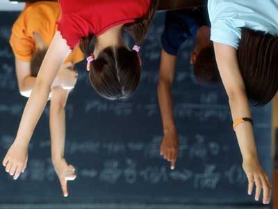 An upside-down photo of children raising their hands in a classroom.
