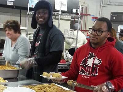 Huskie Service Scholars Blexendi Vixama and Keelan Wright dish up hot meals to the community at Feed’em Soup.