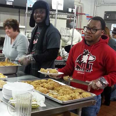 Huskie Service Scholars Blexendi Vixama and Keelan Wright dish up hot meals to the community at Feed’em Soup.