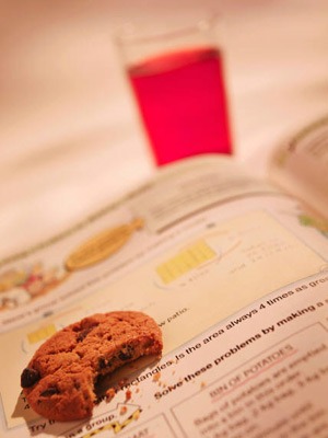 Photo of a half-eaten cookie and a glass of juice with an open textbook