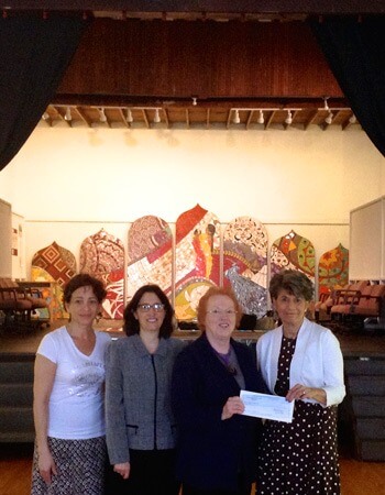 Micki Chulick of DeKalb County Community Foundation presents a Community Needs check to Anna Marie Coveny, director of DeKalb Area Women’s Center. Diane Rodgers, NIU associate professor of sociology and Lucy Sosa, an NIU sociology graduate student, look on.