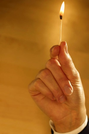 Photo of a hand holding a lit match