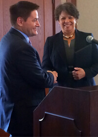 Sharon Banks-Wilkins shakes hands with board chair John Butler following his reading of a resolution in her honor.