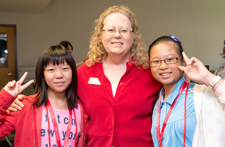 Gail Hayenga, conference and event coordinator in the NIU College of Education’s Office of External & Global Programs, greets two American Summer Education Camp students from the National University of Tainan Affiliated Elementary School.