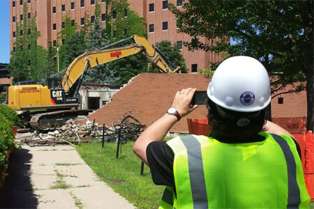 Alex Gelman, director of the NIU School of Theatre and Dance, photographs work to demolish the Stevens Building.