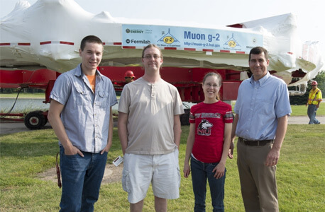 Mike McEvoy, Aaron Epps, Mary Shenk and Professor Mike Eads stand in front of the Muon g-2 magnet during the July 26 move.