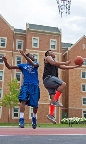 Students play basketball outside New Hall.