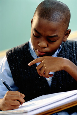 Photo of an African-American boy taking notes in class