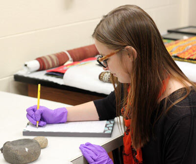 Senior history major Karissa Kessen creates reports on the condition of archaeological material.