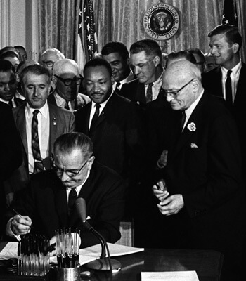 President Lyndon B. Johnson signs the 1964 Civil Rights Act as Martin Luther King Jr. and others look on. Cecil Stoughton, White House Press Office