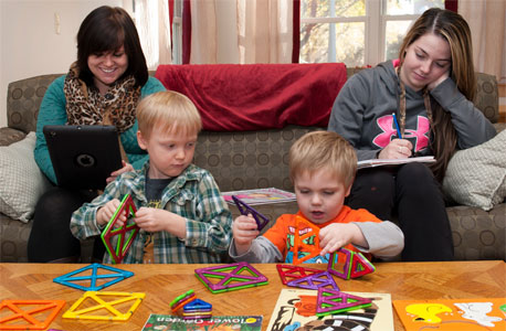 Student-parents Destiny Engels (left) and Heather Theissing study in the Campus Child Care North Corner Room while their sons, Randal and Jeremiah, play.