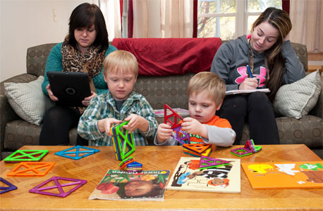 Student-parents Destiny Engels (left) and Heather Theissing study in the North Corner Room of Campus Child Care while their sons, Randal and Jeremiah, play.