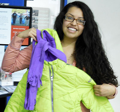 Photo of a Huskie Service Scholar holding a coat and scarf