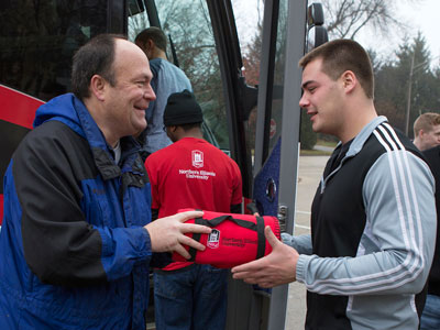 Robert M. Peterson, associate professor and White Lodging Professor of Sales at NIU, hands out NIU fleeces to students boarding the #NIUSalesBus.