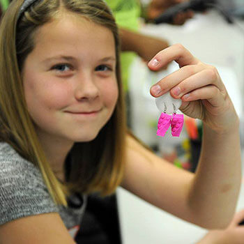3-D printed earrings, proudly displayed here by a STEM Divas participant, are just one of the projects girls have an opportunity to explore in the program.