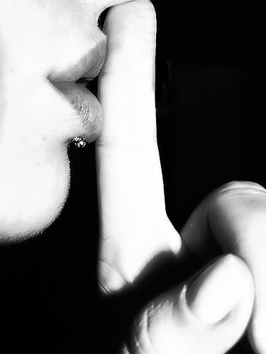 Photo of a woman shushing with finger to lips
