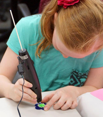A participant in a STEM Divas Saturday class works on her original creation using a 3Doodler, a hand-held 3-D printing device.