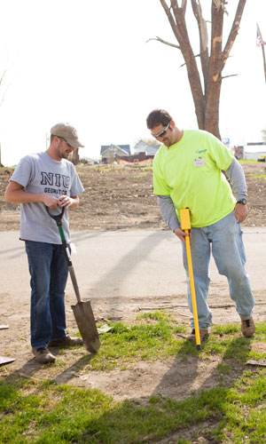 Instructor Kory Allred (right) and NIU student Jeremy Daehne search for buried property corner markers to re-survey parcels of land in Fairdale.