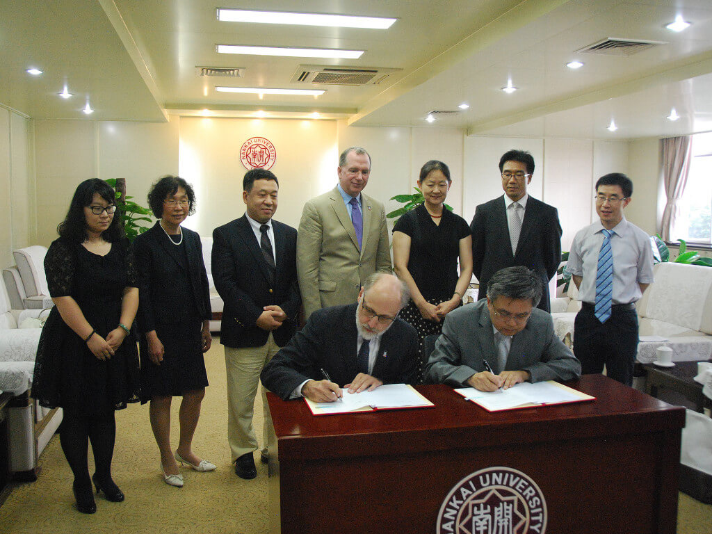 NIU President Doug Baker and Nankai University President Gong Ke sign the NNIC agreement as representatives from each institution look on. 