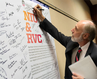 NIU President Doug Baker signs the declaration.