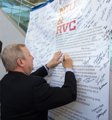 U.S. Sen. Dick Durbin signs his name to a banner celebrating the NIU-RVC Engineering Program.