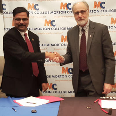 Morton College Interim President Muddassir Siddiqi (left) and NIU President Doug Baker shake hands after signing the reverse transfer agreement during a ceremony Tuesday at the Morton College campus in Cicero.