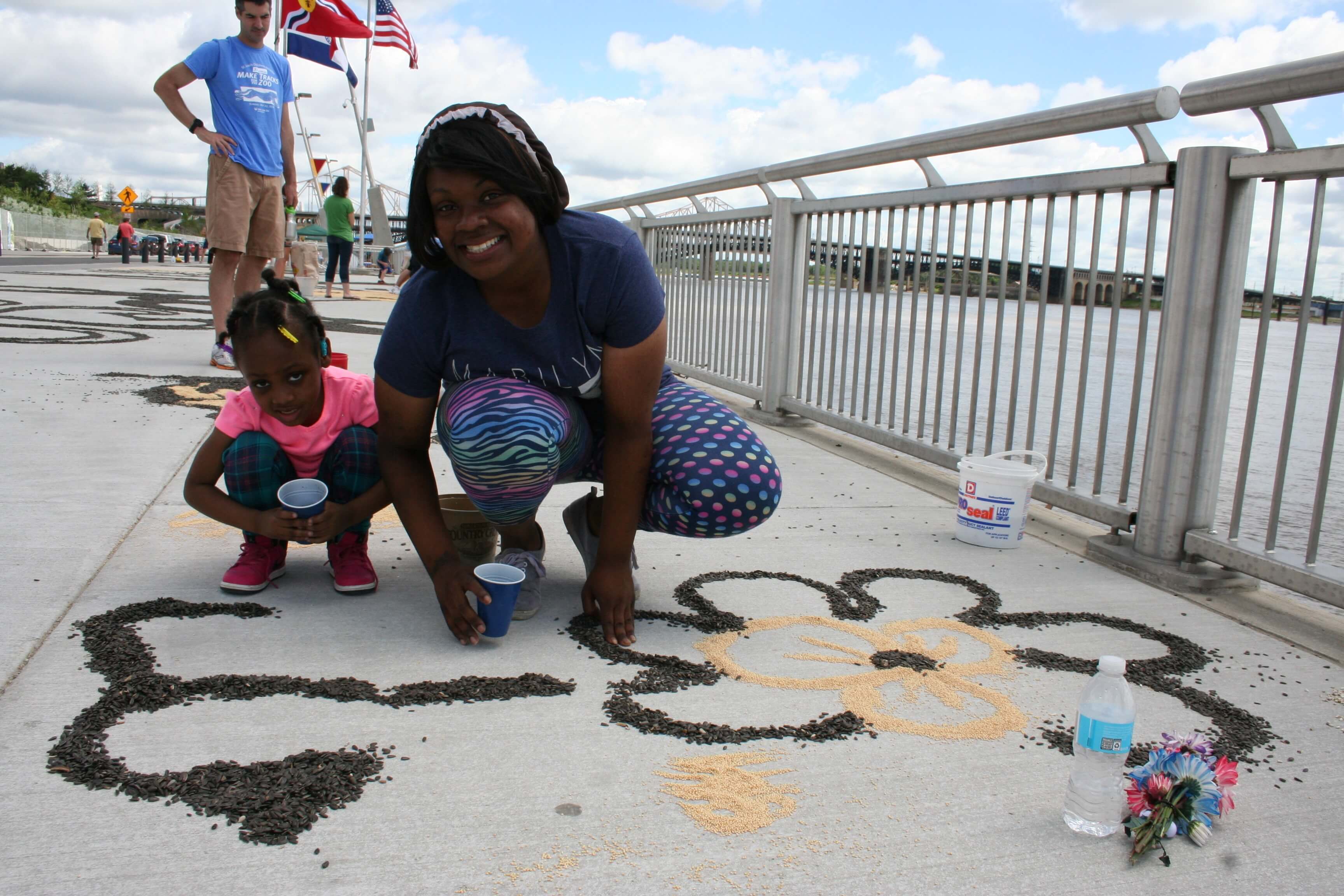 Salina Govan of St. Louis and her daughter, Kristyahna Bradshaw, help decorate the Gateway Arch riverfront with birdseed art.